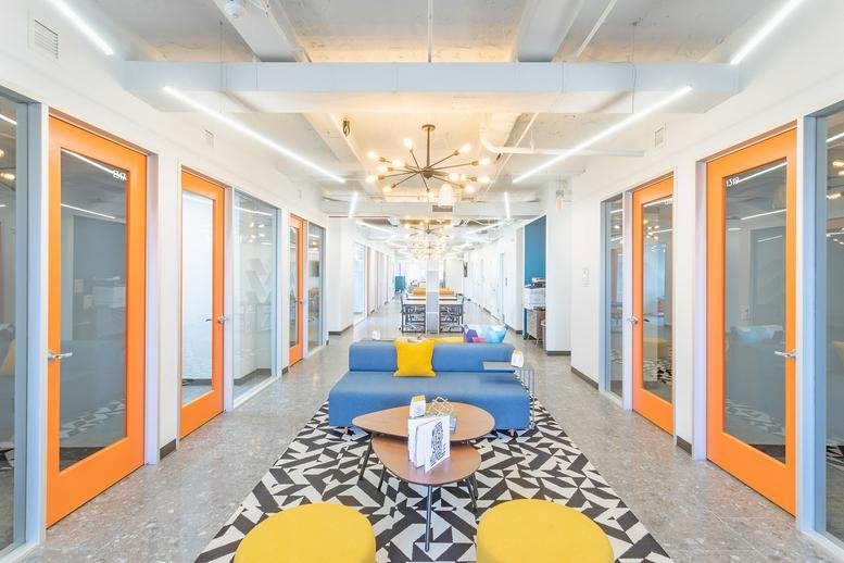 Spacious communal lounge at 69 State Street, Albany (NY) with bright orange doors and a geometric rug.