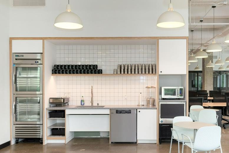 Modern communal kitchen at 6900 Dallas Parkway, Legacy Town Center with white tiling and pendant lighting.