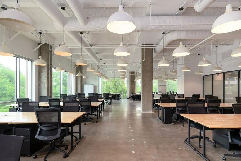 Open-plan workspace at 6900 Dallas Parkway, Legacy Town Center featuring rows of desks and industrial lighting.