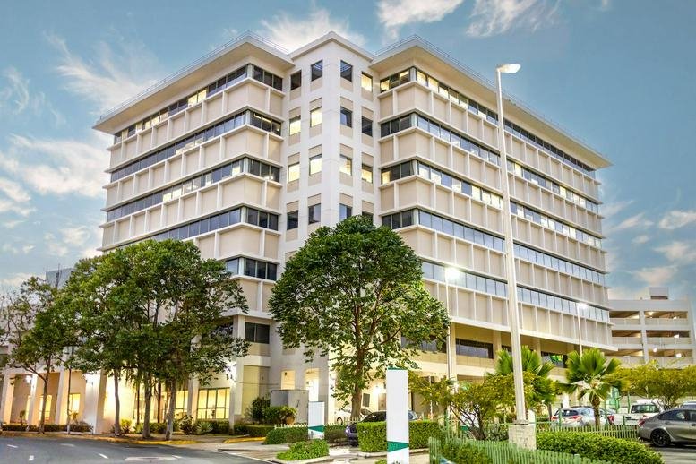 Exterior view of the multi-story San Patricio Office Center building with modern architecture and green trees.