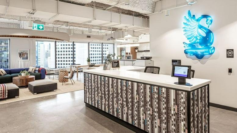 Modern reception area at Stephen Avenue Place with a large glowing blue swan logo and a stylish front desk.