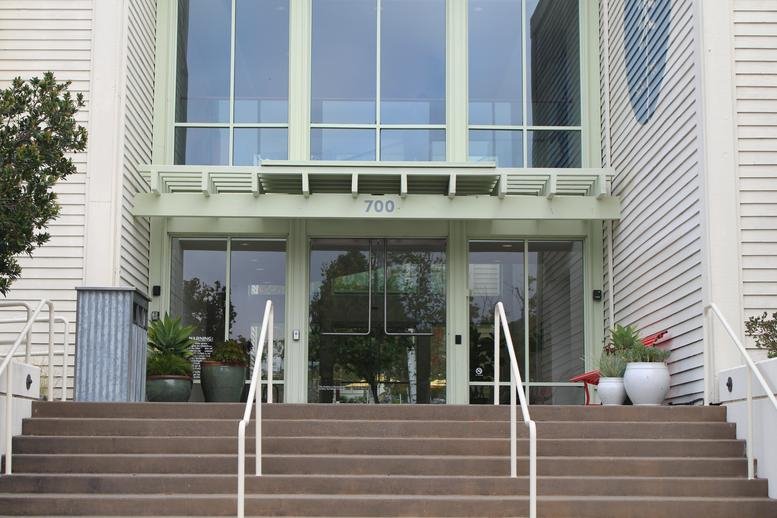 Exterior view of the main entrance with steps leading to glass doors at 700 Larkspur Landing Circle.