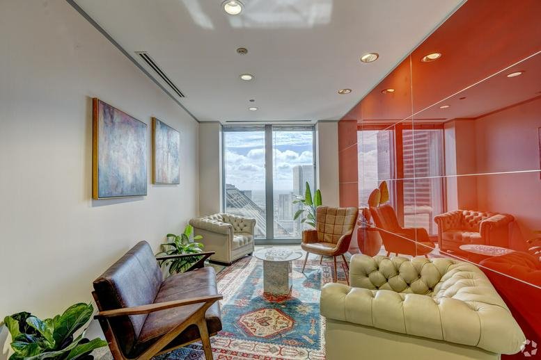 Stylish lounge area with leather seating and a vibrant orange glass partition wall.