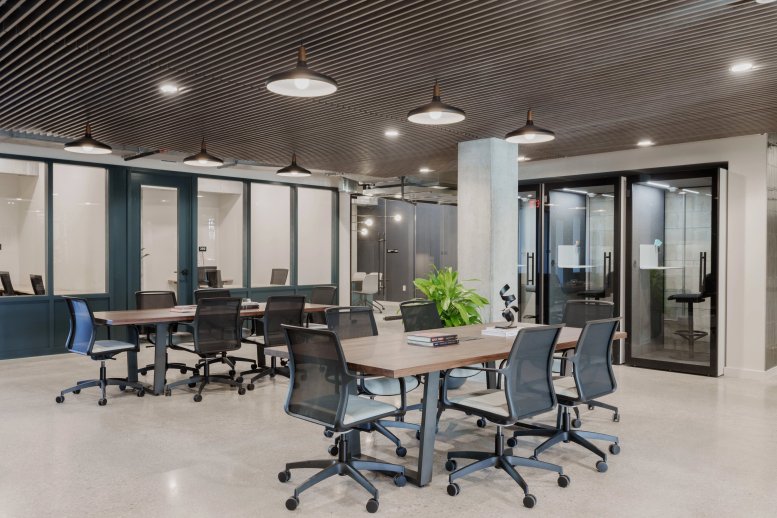 Spacious communal coworking area at 7001 Burnet Road with wooden tables and industrial ceiling.