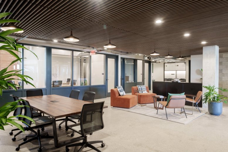 Modern reception lounge at 7001 Burnet Road featuring orange armchairs and a sleek black desk.