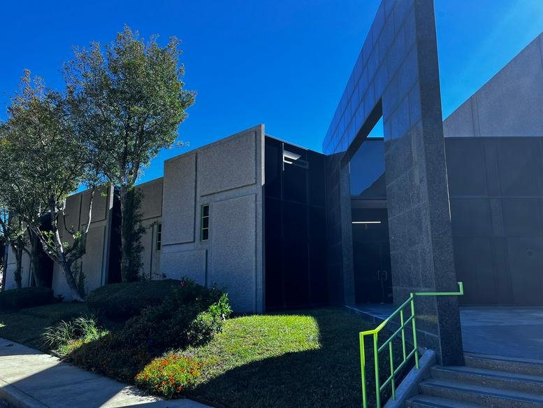 Modern architectural exterior of the office building at 7055 Old Katy Road with sharp angles and green railings.