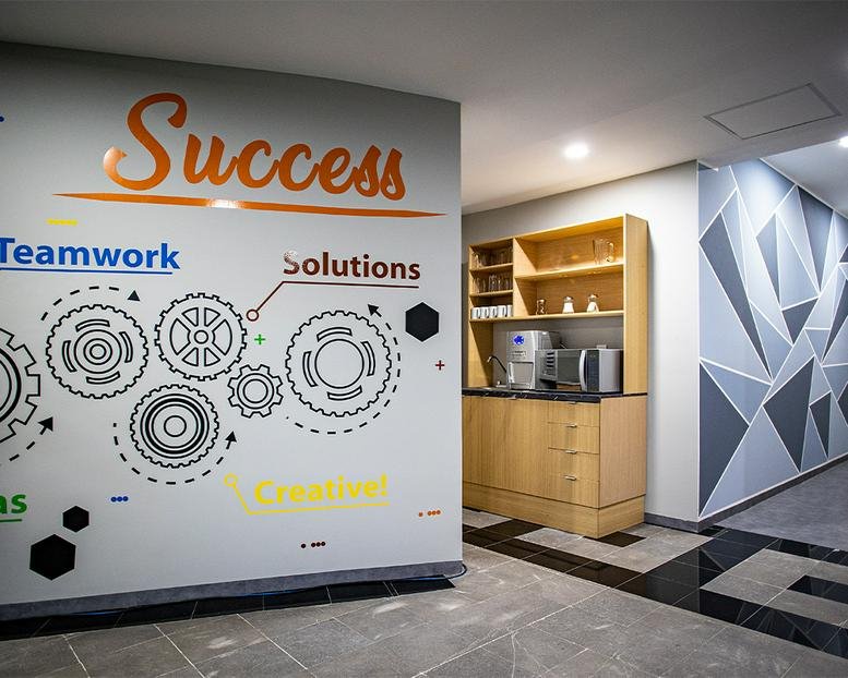 Reception area at 71, Parque de Granada featuring success-themed wall graphics and a coffee station.