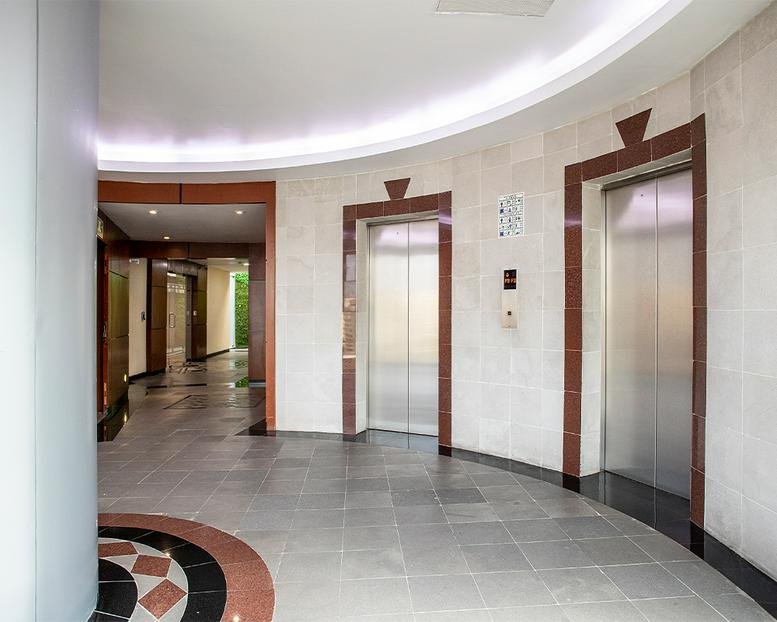Modern elevator lobby at 71, Parque de Granada with marble floors and curved walls.