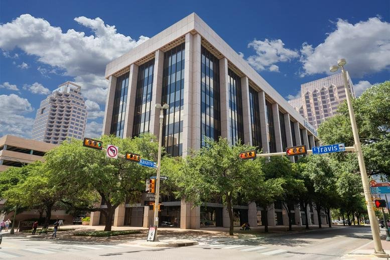 Exterior view of the multi-story Travis Park Plaza building under a blue sky.