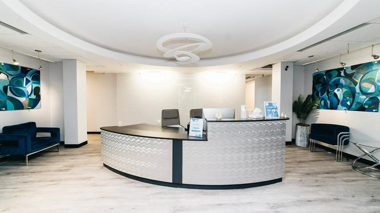 Bright reception area at 7375 Executive Place, Suite 400 with a curved desk and blue abstract art.