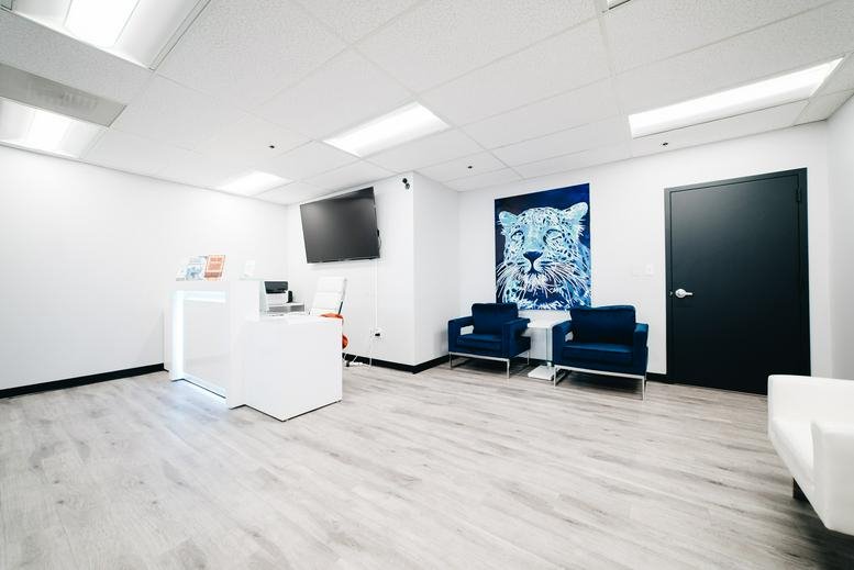 Reception lobby at 7404 Executive Place, Suite 400 with white desk, blue chairs, and lion wall art.