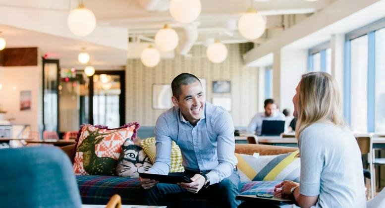 Spacious communal lounge at 750 N San Vicente Boulevard with colorful cushions and globe lighting.