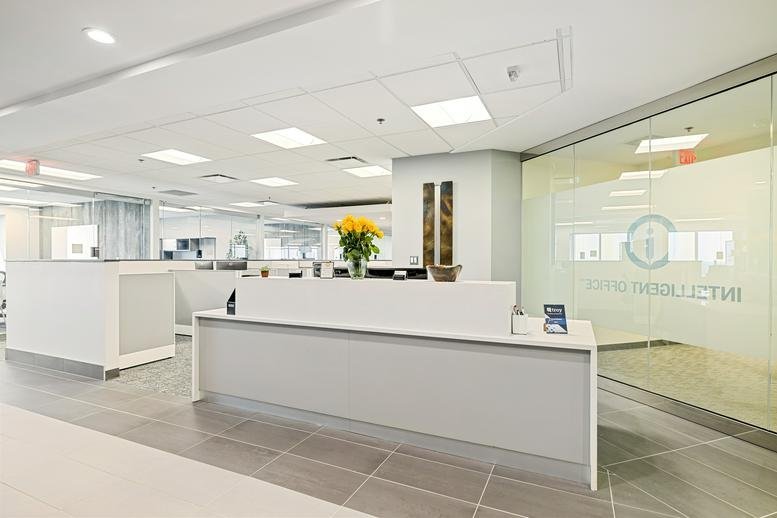 Modern white reception desk with a vibrant bouquet of yellow flowers and frosted glass partition.