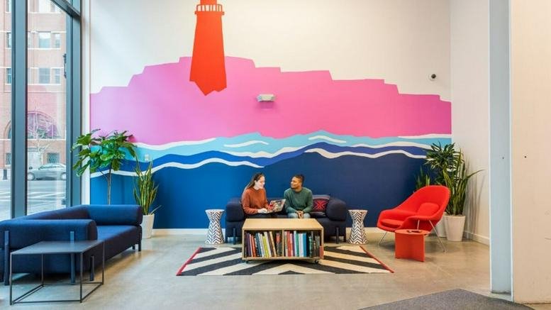 Spacious lounge at 77 Sleeper Street featuring a vibrant mural of a lighthouse over blue waves.