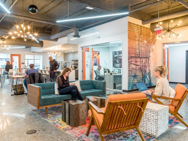 Colorful open-plan lounge at 790 N Milwaukee St with teal sofas and vibrant area rug.