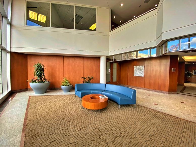 Spacious lobby at 7918 Jones Branch Drive with blue curved sofas and wood-paneled walls.