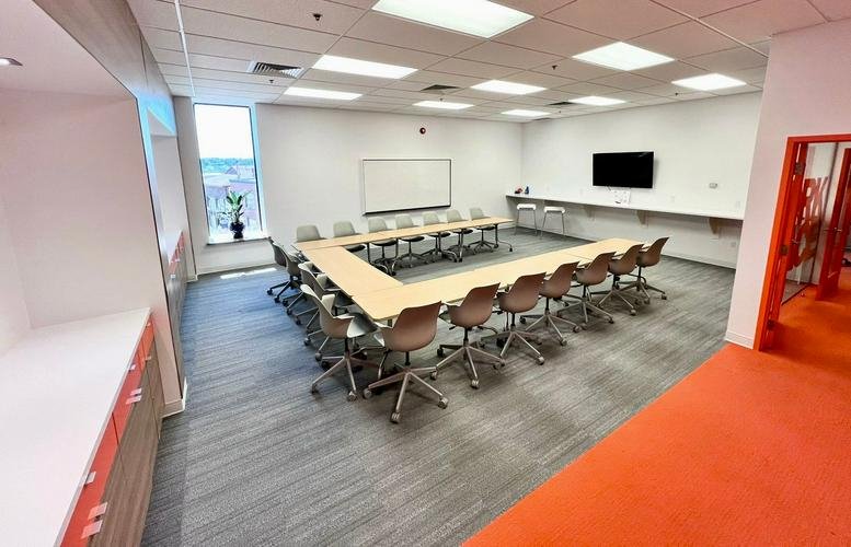 Large meeting room at 795 Main Street, Suite 300 with U-shaped table, orange accent floor and whiteboard.