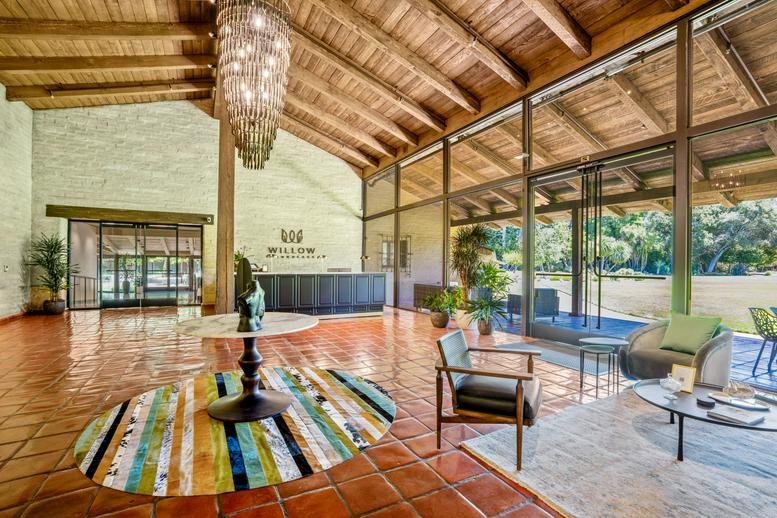 Spacious sunlit lobby with high timber ceilings, tile floors, and a modern reception desk.