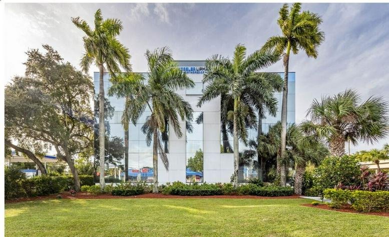 Exterior view of the glass-facade building at 800 East Cypress Creek Road with lush palm trees.