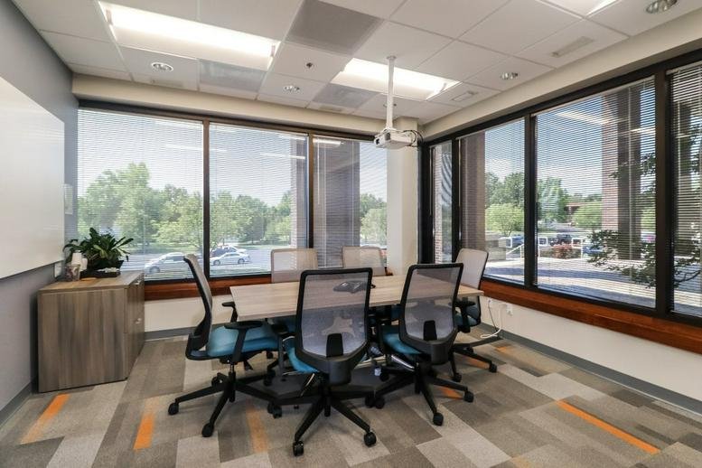 Meeting room at 8101 College Boulevard Suite 100 with large windows, projector, and seating for six.