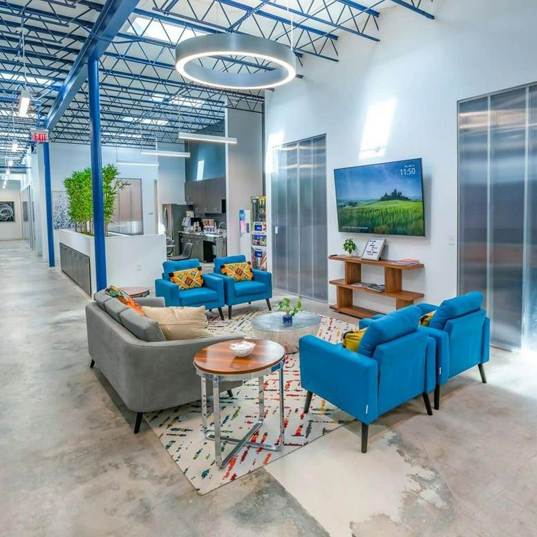 Spacious communal lounge at 8215 Long Point Road with blue armchairs and industrial ceilings.