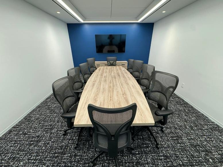 Conference room at 825, 3rd Avenue, Manhattan, New York City featuring a wood table and blue accent wall.