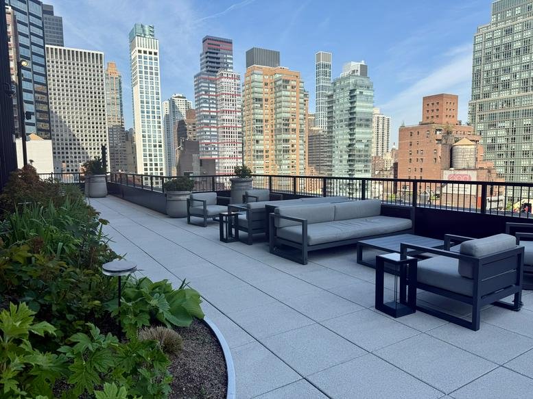 Spacious rooftop terrace with modern grey outdoor furniture overlooking the Manhattan skyline.
