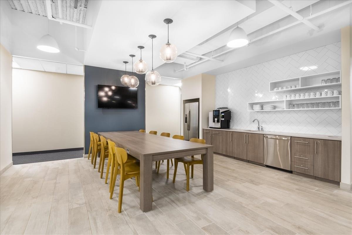 Spacious communal kitchen and dining area with wood-tone cabinets and a long harvest table.
