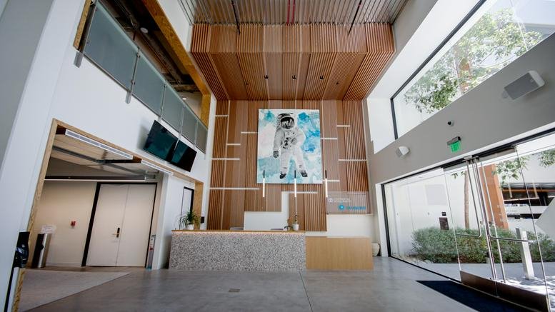 Spacious wood-paneled lobby and reception area at 840 Apollo St with large astronaut artwork.