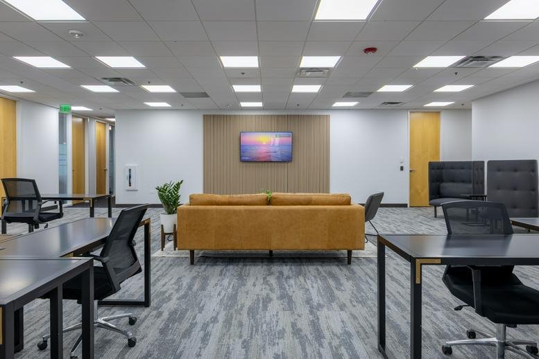 Open-plan workspace featuring a tan sofa and several modern desks.
