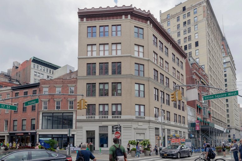 Exterior view of the tan brick building at 860 Broadway located at a busy intersection.