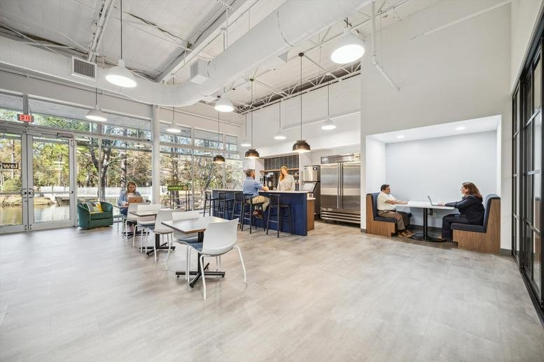 Open communal cafe space with varied seating and floor-to-ceiling windows.