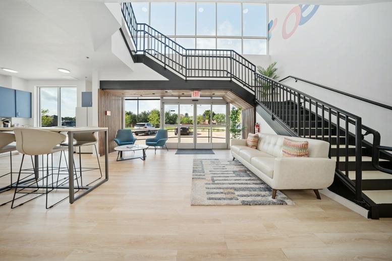 Bright lobby at 8720 Silverado Trail with a modern white sofa and a grand black staircase.