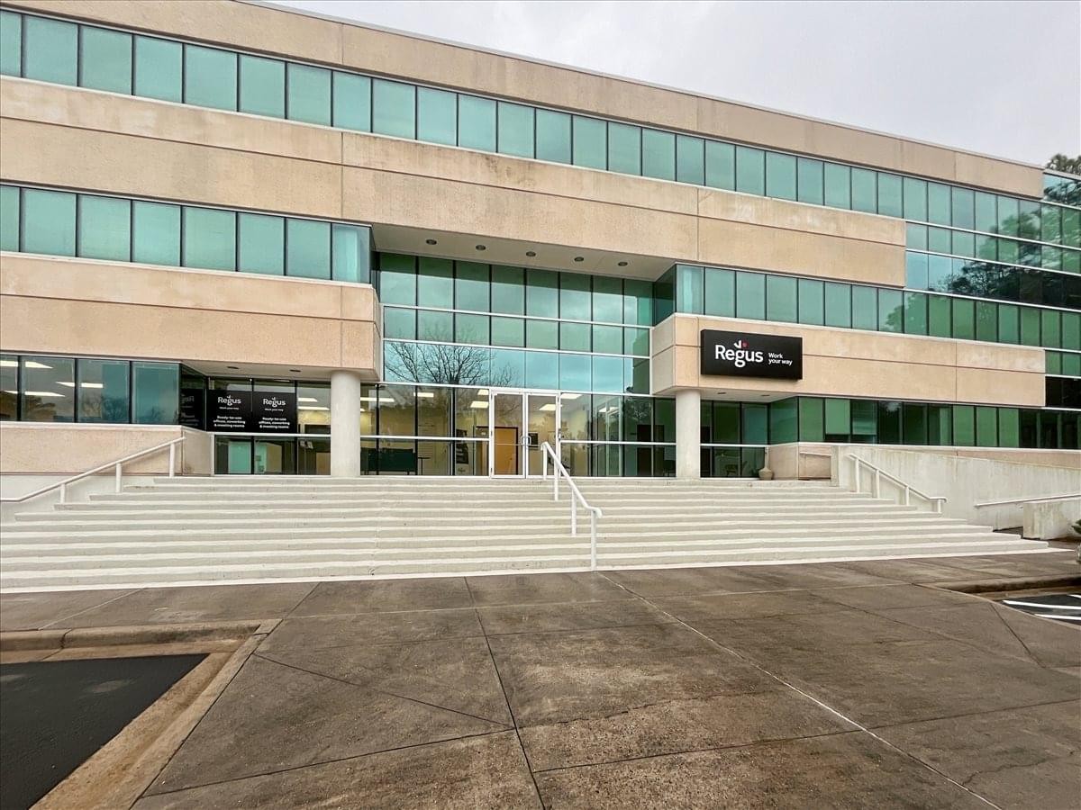 Wide exterior shot showing the multi-story office building with stone and glass facade.