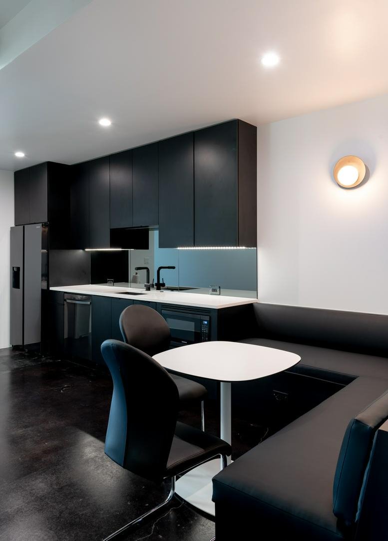Modern communal kitchen at 907 Pollard Street, Suite 100 featuring sleek black cabinets and a built-in booth.