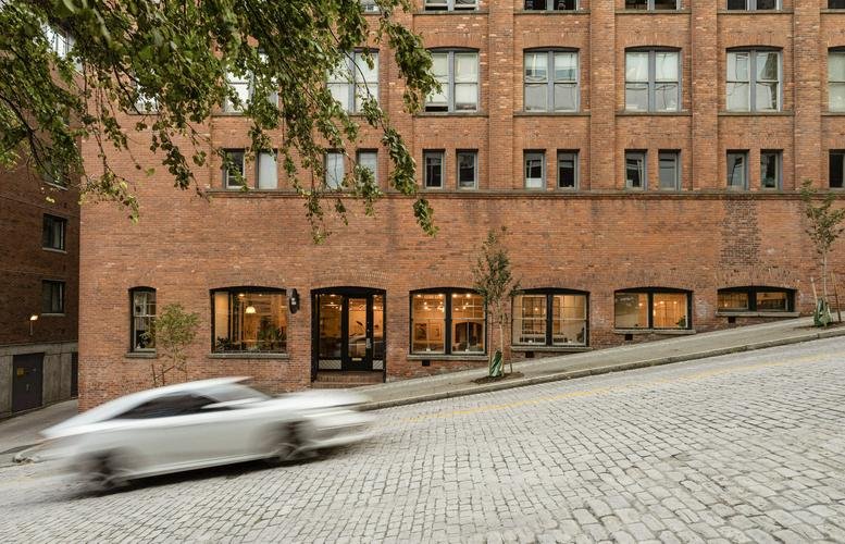 Exterior brick building view showing multiple floors on a sloped cobblestone street.
