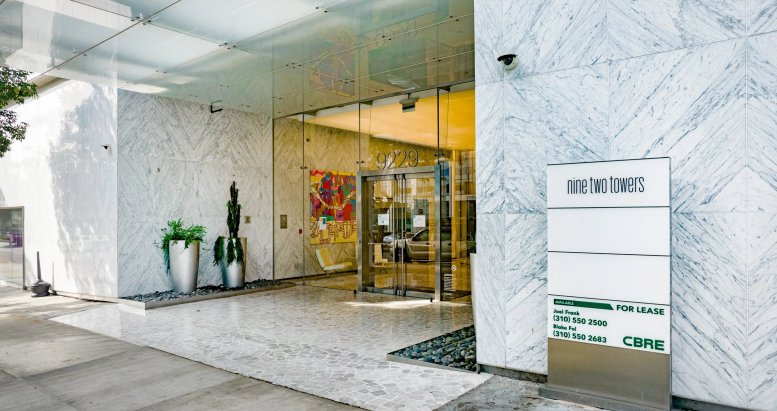 Exterior entrance of the Nine Two Towers building featuring marble walls and a modern glass canopy.