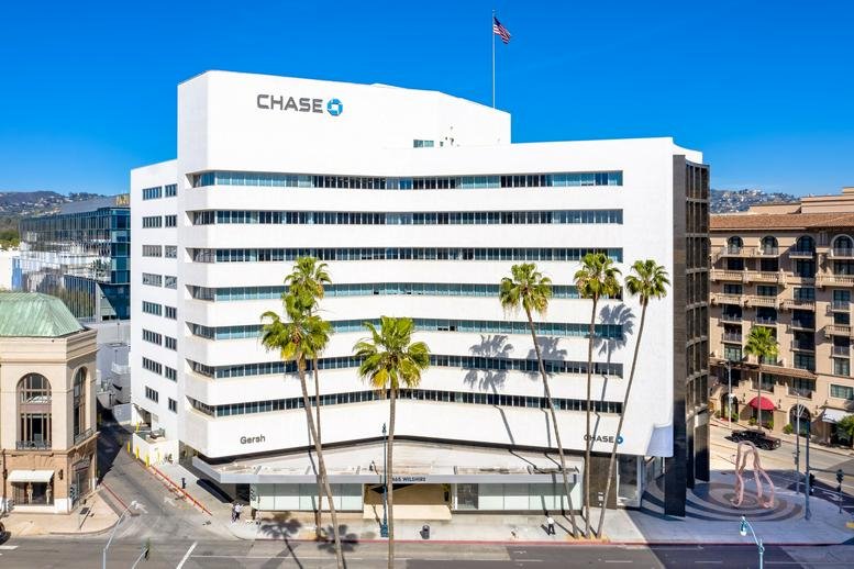 Exterior view of the white facade of Wilshire Beverly Center featuring palm trees and blue sky.
