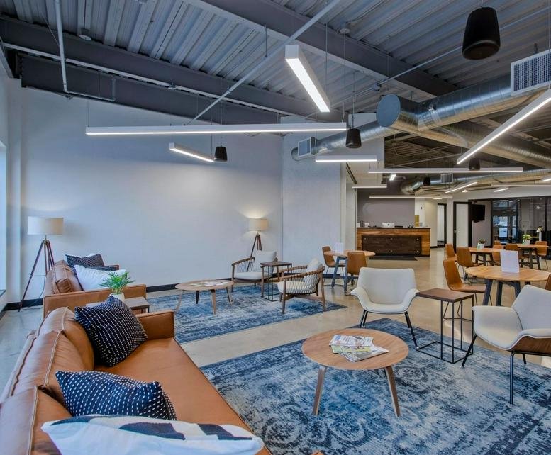 Spacious communal lounge area with leather sofas, blue patterned rugs, and modern industrial lighting.