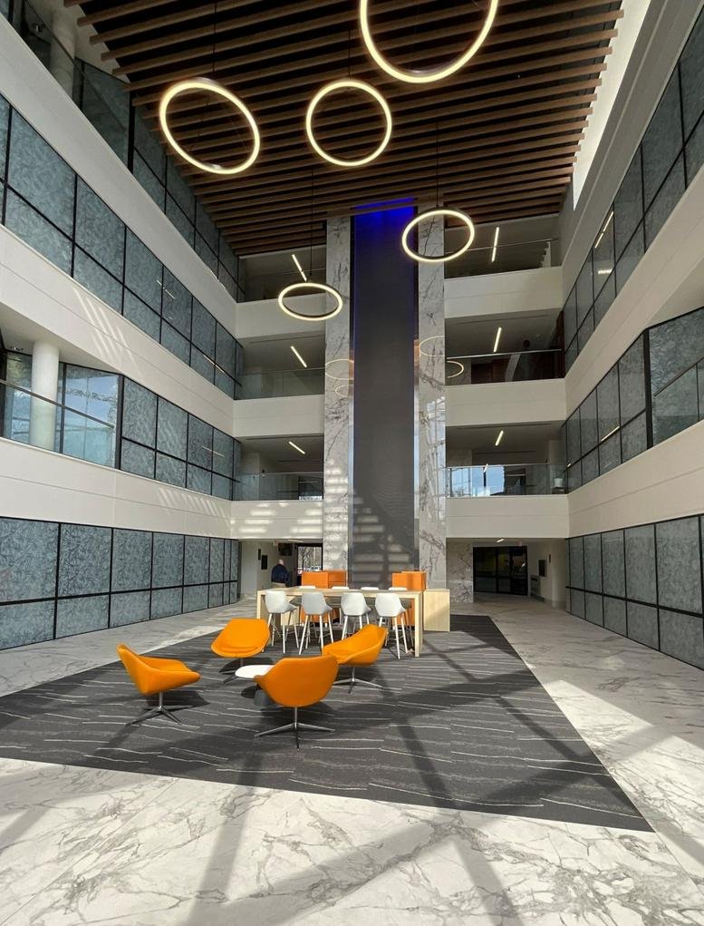 Modern multi-story atrium lobby with marble floors and orange lounge seating.