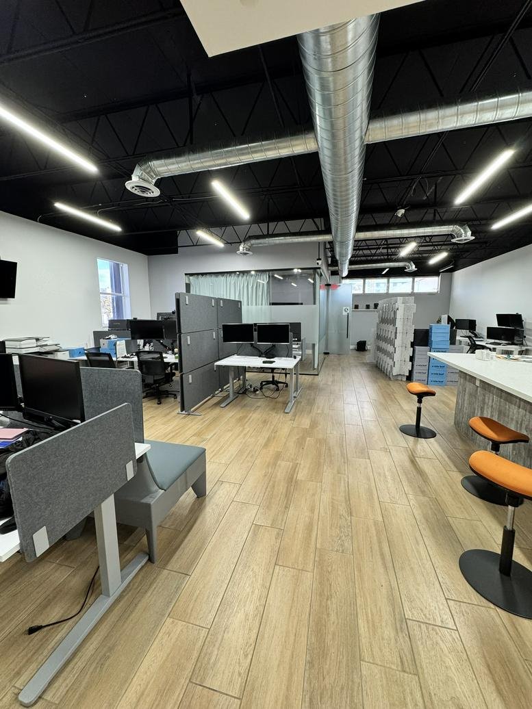 Modern workspace featuring standing desks and orange bar stools at a high-top counter.