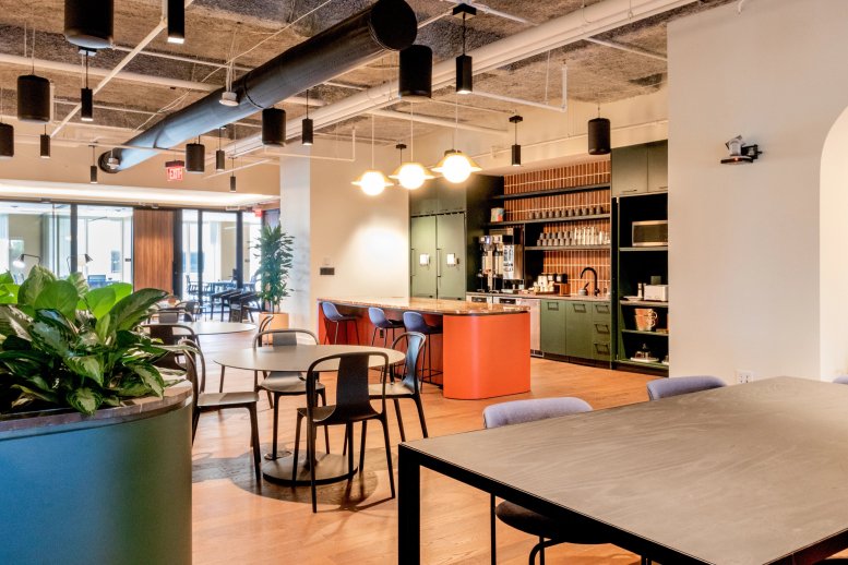 Spacious communal kitchen and dining area with a curved orange island and modern lighting.