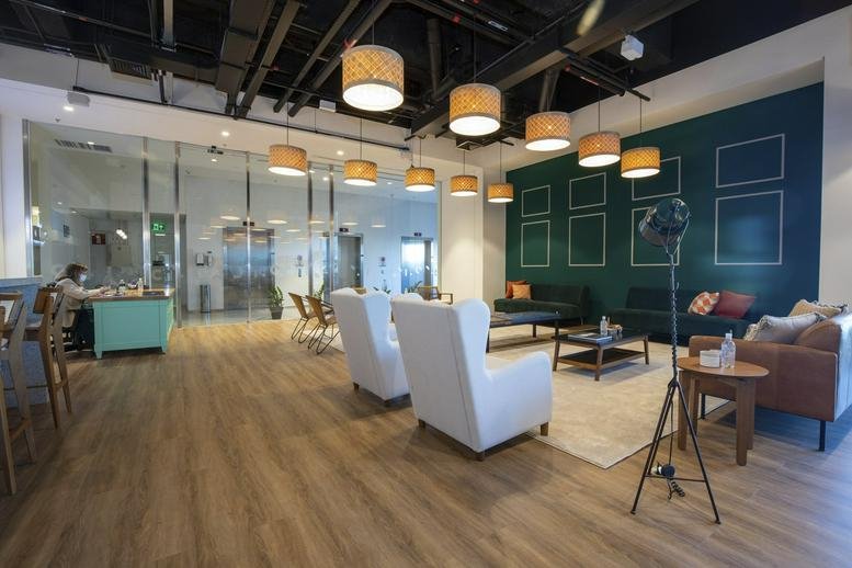 Spacious lounge at Concordia Corporate with white armchairs, wooden floors, and a dark green feature wall.