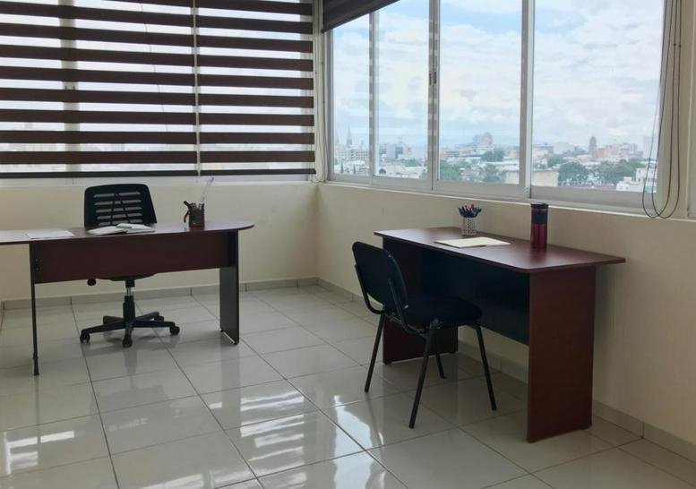 Spacious corner office with two wooden desks and expansive city views through large windows.