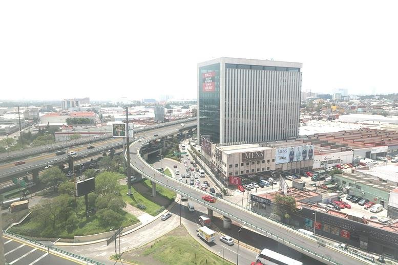 Exterior view of the commercial building at Av. Primero de Mayo 15 near a major highway interchange.