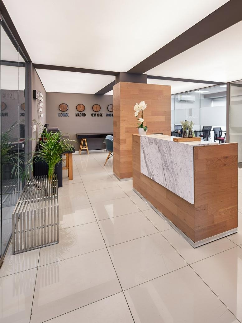 Professional reception area with a wood and marble desk, world clocks, and polished tile floors.