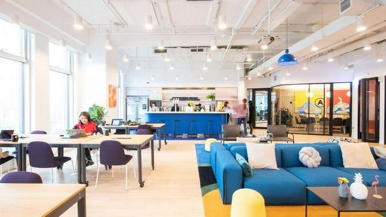 Spacious interior of Avenida Circuito Frida Kahlo 303 with blue sofas, workspaces, and a coffee bar.