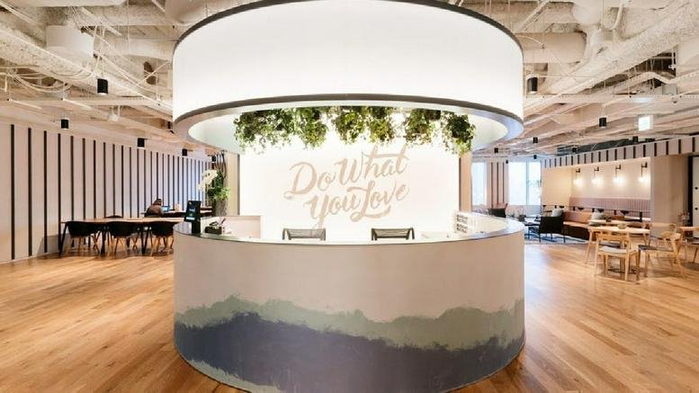 Bright reception area at Avenida Corrientes 800 with a circular desk and greenery under a large light fixture.