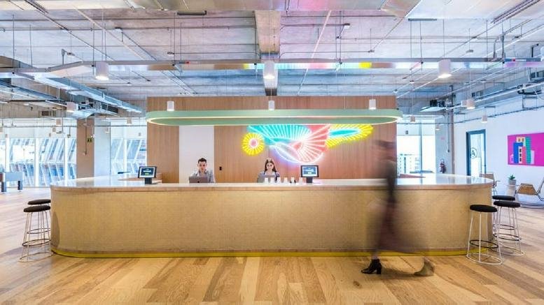 Modern reception desk at Avenida De Las Americas 1254 featuring a colorful bird mural and light wood floors.