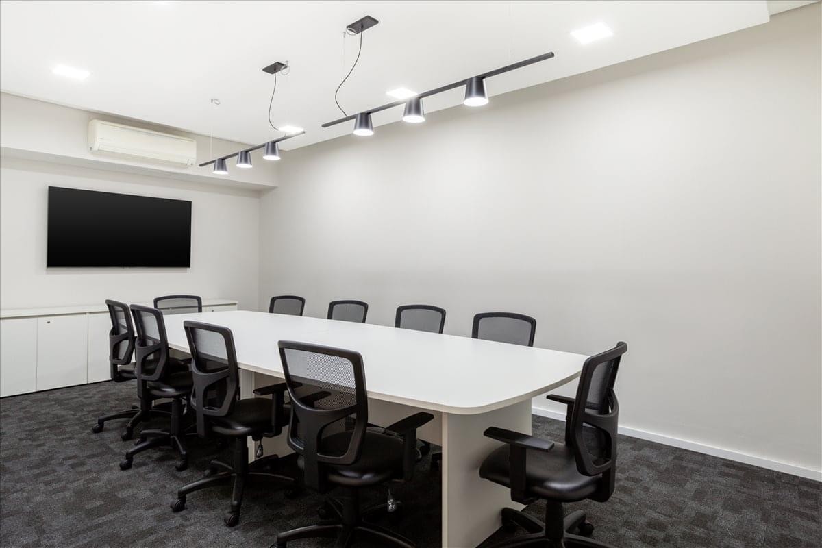 Meeting room at Avenida dos Autonomistas 2561 with a long white table and black mesh chairs.